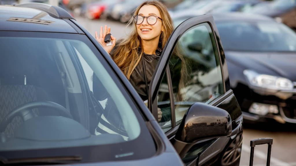 Renter holding car keys at an open vehicle door, ready to drive